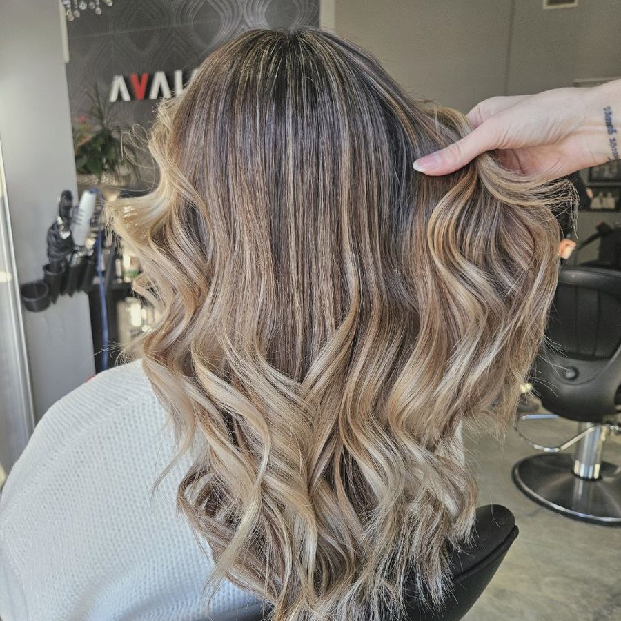 Woman's long blonde balayage hair with loose waves at Avalon Salon Calgary