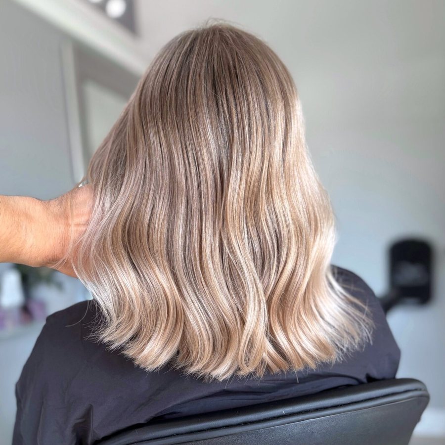 Woman's shoulder-length blonde hair with soft waves, finished at Avalon Salon Calgary